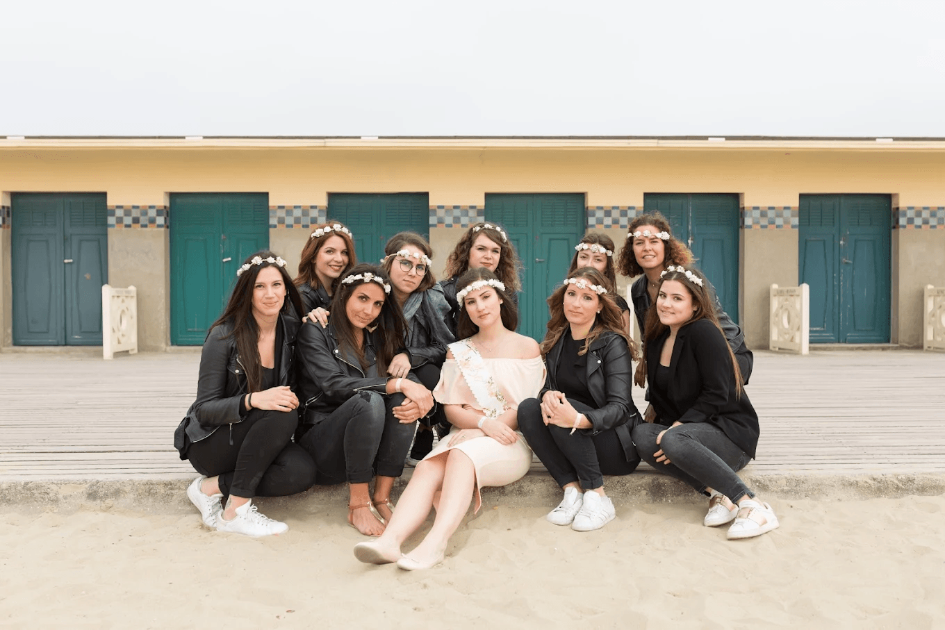 Future mariée et ses copines posant devant les cabines de plage de Deauville avec des couronnes de fleurs.
