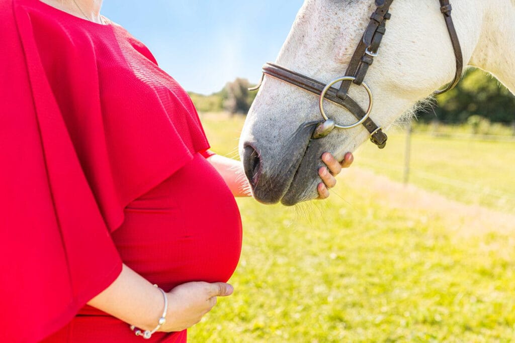 gros plan sur le ventre d'une femme enceinte et son cheval près du studio M2 PHotographie à Honfleur.