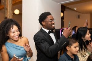 Un invité souriant photographie les mariés avec son smartphone pendant la soirée de mariage à Deauville.