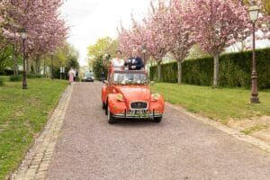 Les mariés arrivent au Domaine d'Aslan à bord d'une 2CV rouge vintage.
