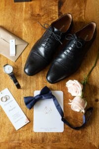 Alliances, nœud papillon bleu marine et chaussures du marié pour un mariage élégant en Normandie.