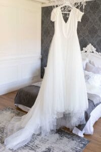 Robe de mariée fluide suspendue dans la belle chambre du Domaine d'Aslan.