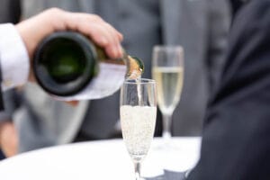 Serveur versant une flûte de champagne lors du vin d'honneur du mariage en Normandie.