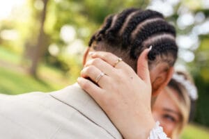 Le marié enlace sa femme, dévoilant leurs alliances de mariage en or et diamants.