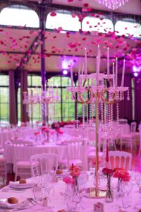 Décoration de table de mariage luxueuse avec grands candélabres en cristal et fleurs roses.