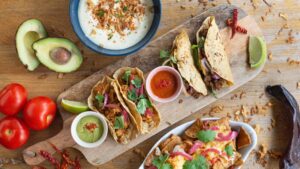 Plateau de tacos mexicains colorés avec guacamole et piment, photographie culinaire dynamique.