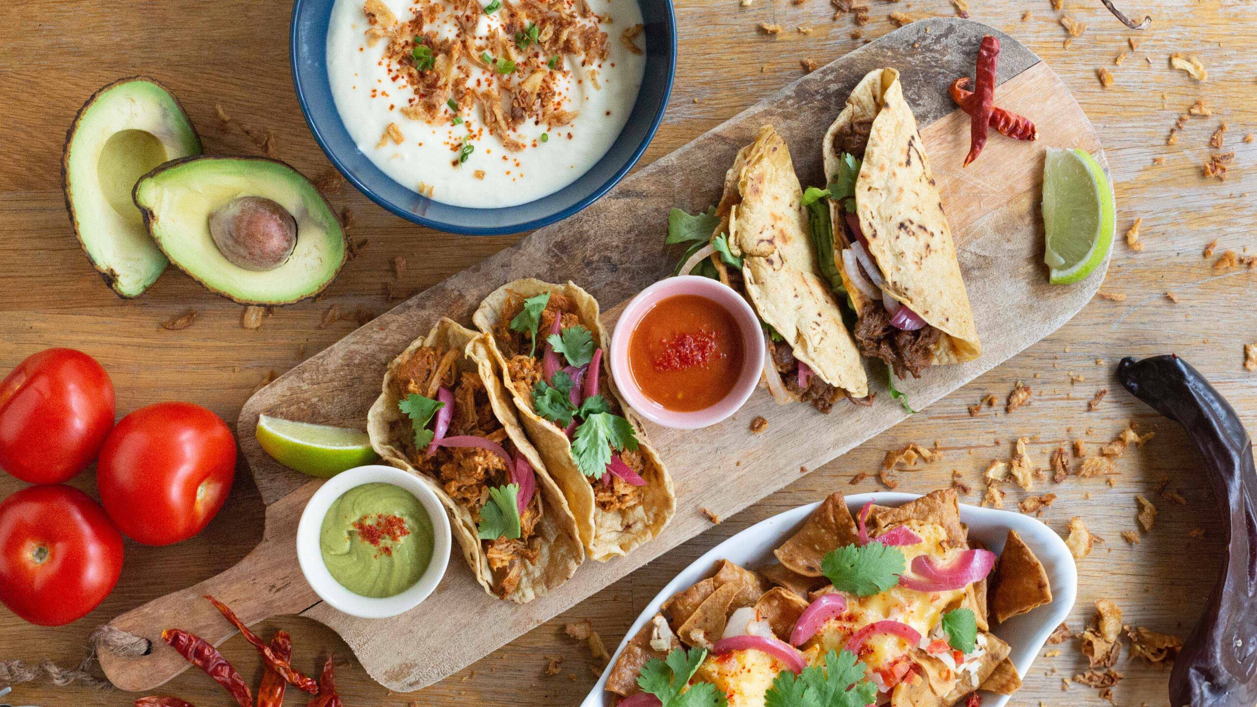 Plateau de tacos mexicains colorés avec guacamole et piment, photographie culinaire dynamique.