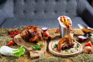 Poulet rôti traditionnel présenté sur un lit de foin pour un esprit ferme et terroir.