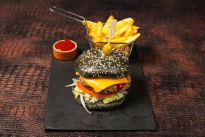 Burger gourmet au pain noir (charbon végétal) servi avec frites croustillantes.