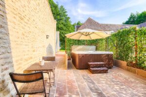 Aménagement extérieur avec jacuzzi et terrasse en pierre pour une location de vacances au Domaine de la Tour.