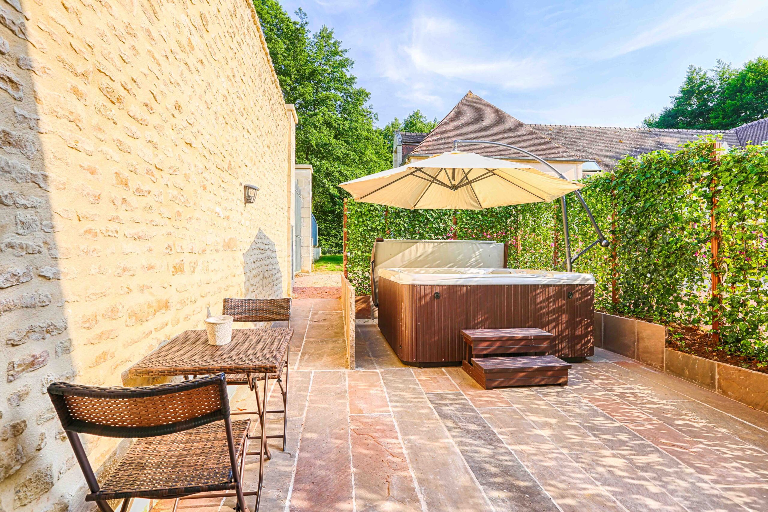 Aménagement extérieur avec jacuzzi et terrasse en pierre pour une location de vacances au Domaine de la Tour.