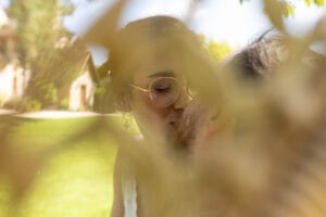 Photo de couple artistique avec les mariés flous derrière un feuillage lumineux.
