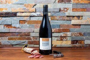 Bouteille de vin rouge et saucisson sec, photographie de produits pour domaine viticole.