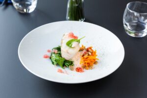 Mise en valeur d'un plat de poisson gastronomique avec émulsion et légumes croquants.