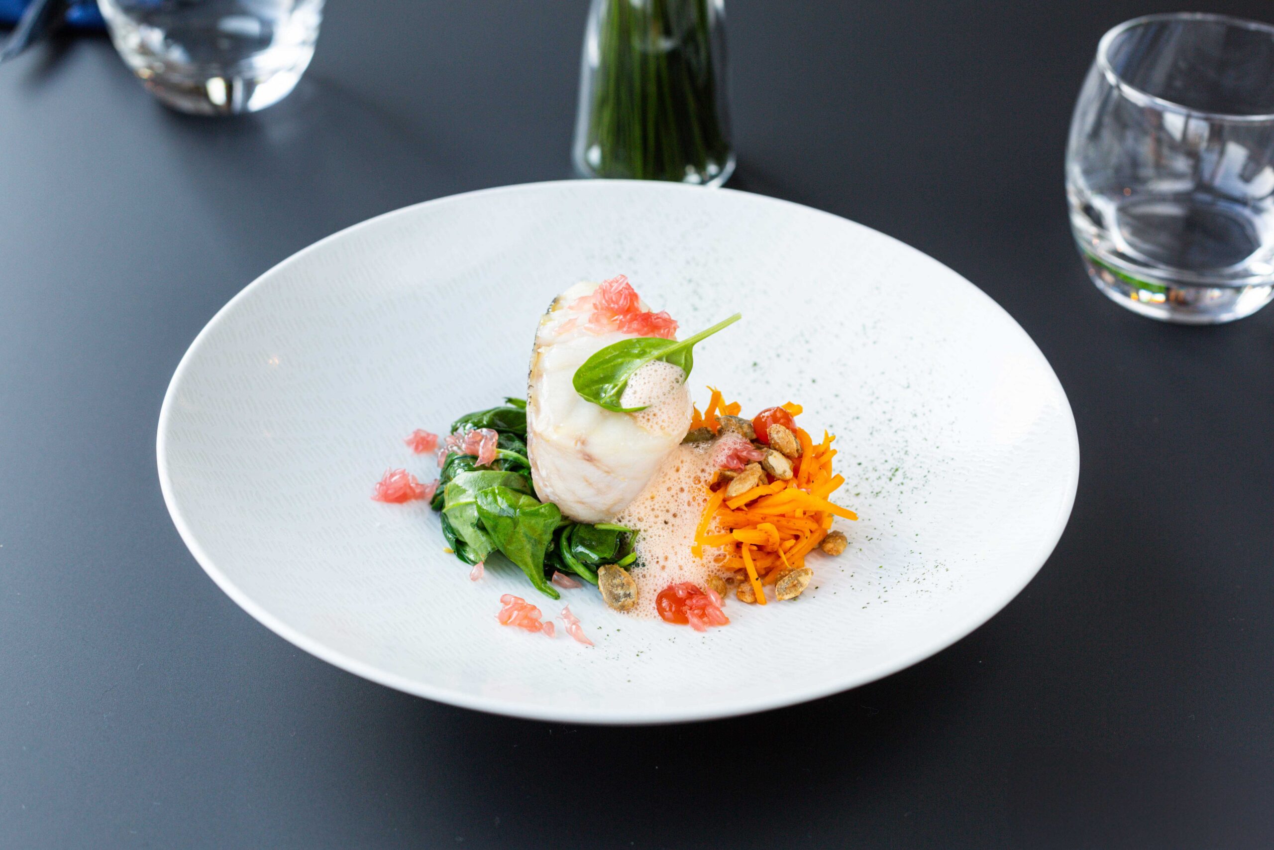 Mise en valeur d'un plat de poisson gastronomique avec émulsion et légumes croquants.