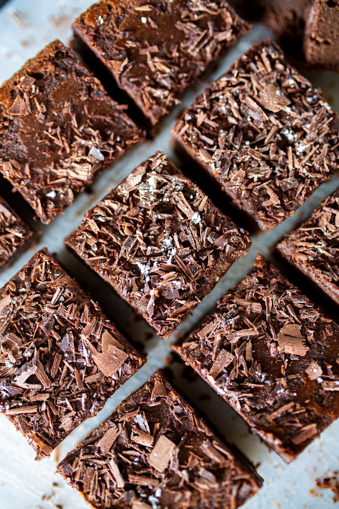 Détail de carrés de brownie au chocolat noir saupoudrés de copeaux de cacao.