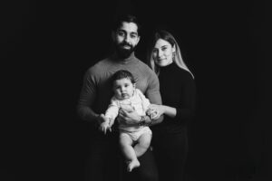 Portrait de famille élégant en noir et blanc réalisé en studio avec des parents et leur bébé.
