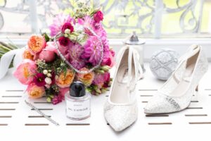 Accessoires de la mariée avec parfum Byredo, chaussures à paillettes et bouquet coloré.