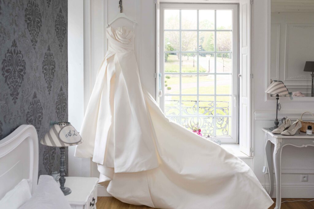 Superbe robe de mariée au bustier drapé suspendue lors des préparatifs au Havre