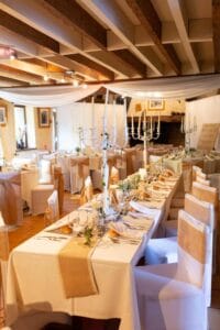 Décoration de table de mariage champêtre avec petits vases en verre, fleurs fraîches et rondins de bois.