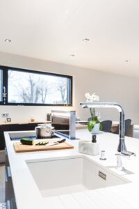 Cuisine moderne avec îlot central blanc et électroménager haut de gamme intégré.