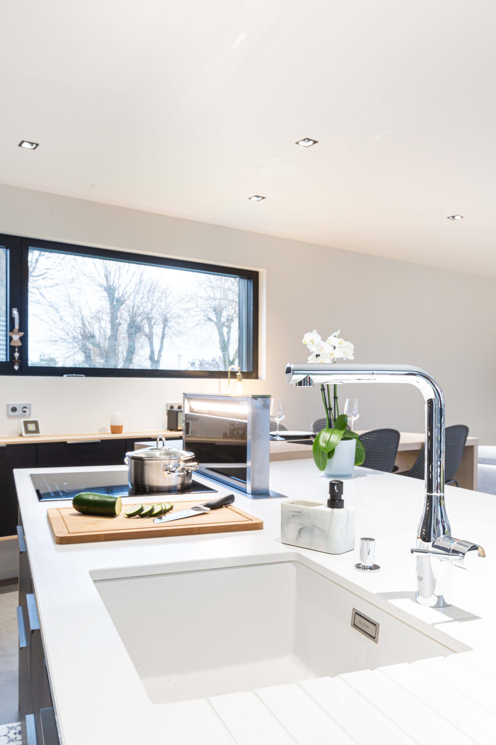 Cuisine moderne avec îlot central blanc et électroménager haut de gamme intégré.