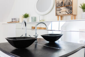 Détail d'une salle de bain moderne avec vasque noire et grand miroir.