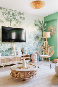 Salon tendance avec papier peint panoramique jungle et mobilier scandinave pour Airbnb.