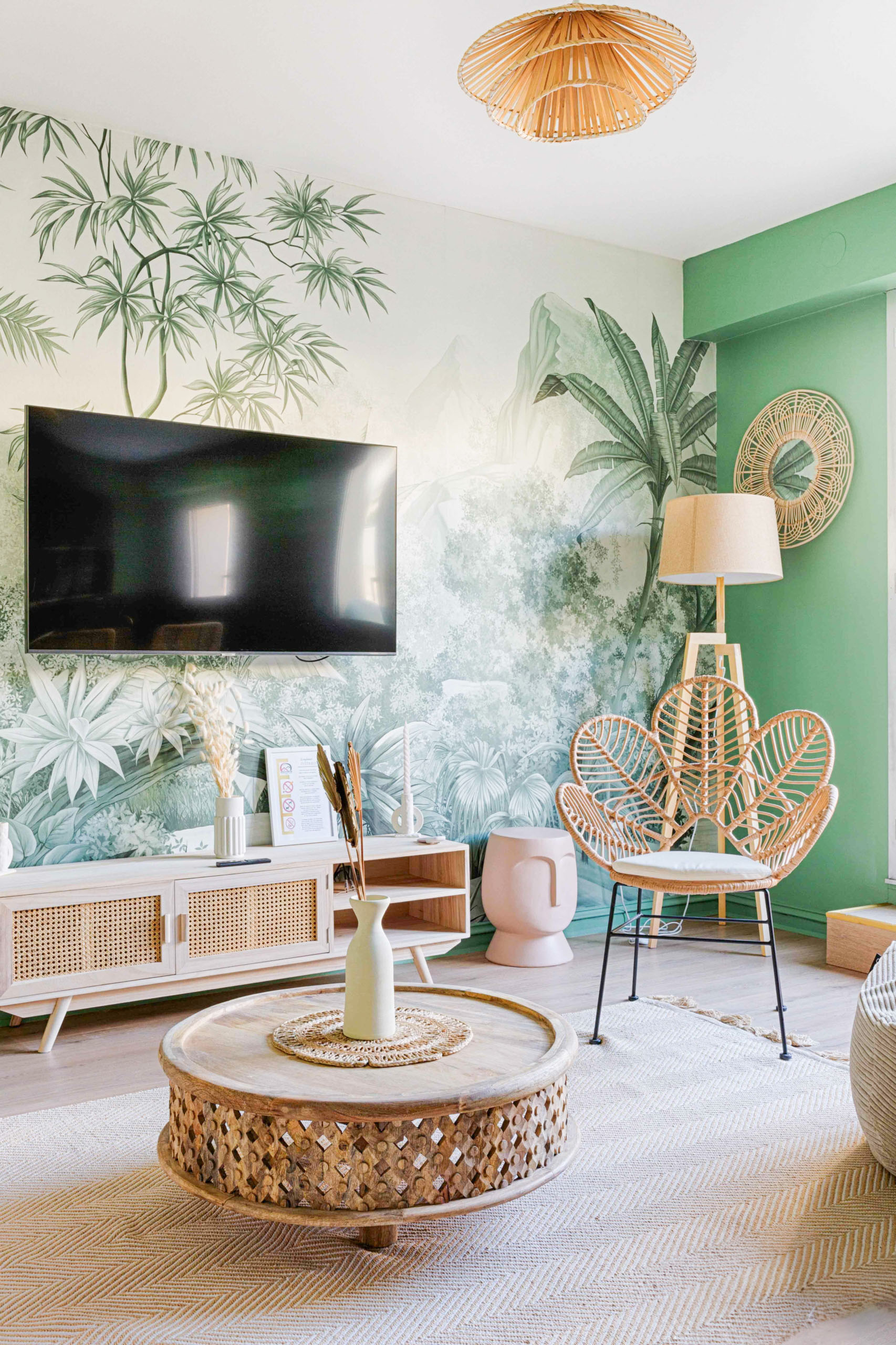 Salon tendance avec papier peint panoramique jungle et mobilier scandinave pour Airbnb.