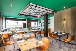 Salle de restaurant au design moderne avec plafond vert et mobilier industriel.