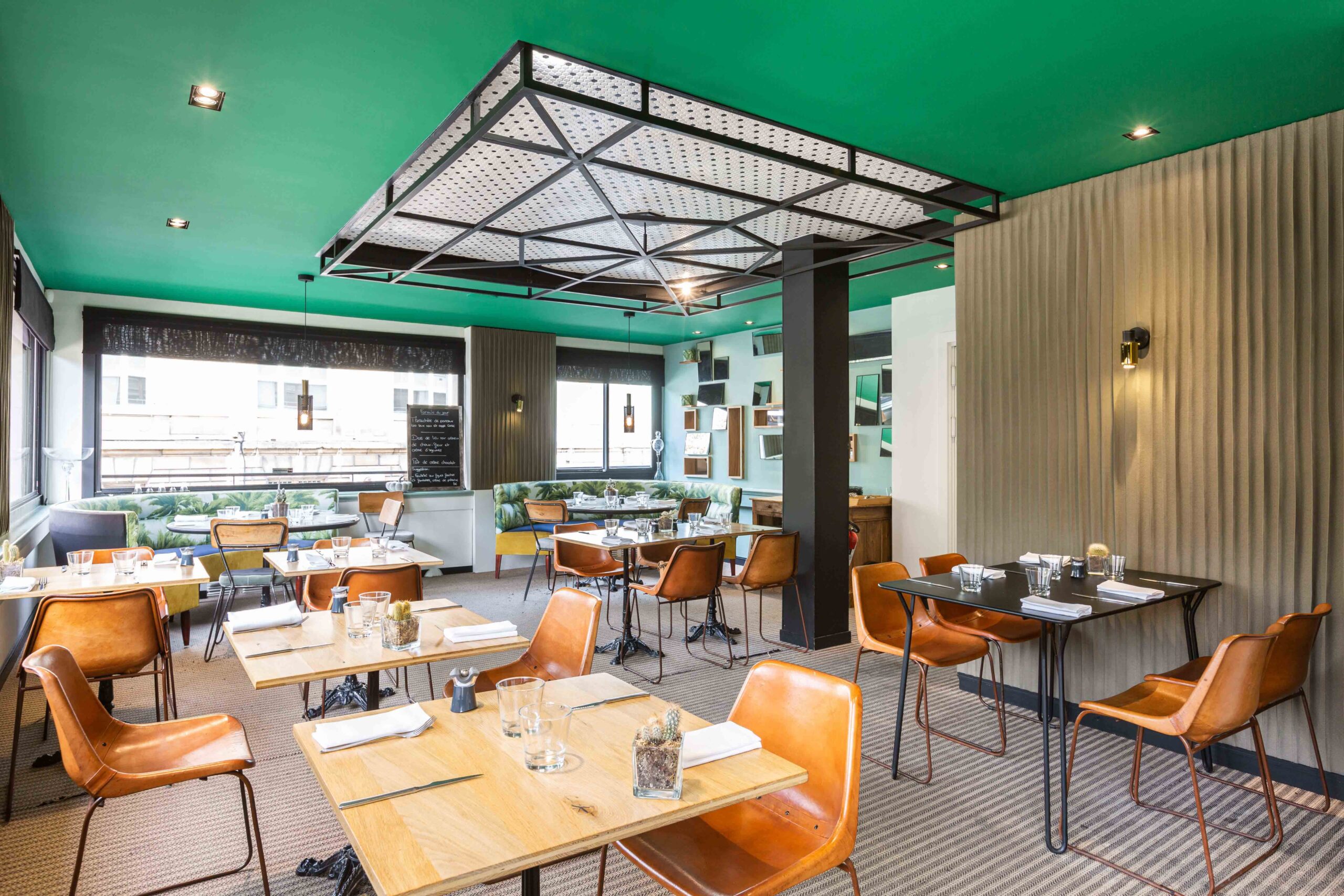 Salle de restaurant au design moderne avec plafond vert et mobilier industriel.