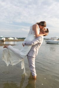 Séance photo de couple romantique et amusante les pieds dans l'eau à la fin de leur mariage.