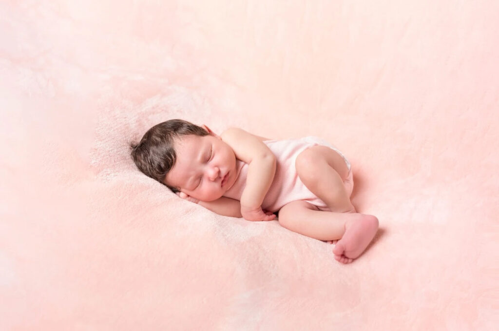 Séance photo bébé fille sur un tapis de fourrure rose poudré en Normandie.