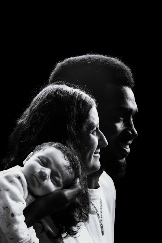 Portrait artistique de profil en noir et blanc d'une famille et leur bébé, photographe Honfleur.
