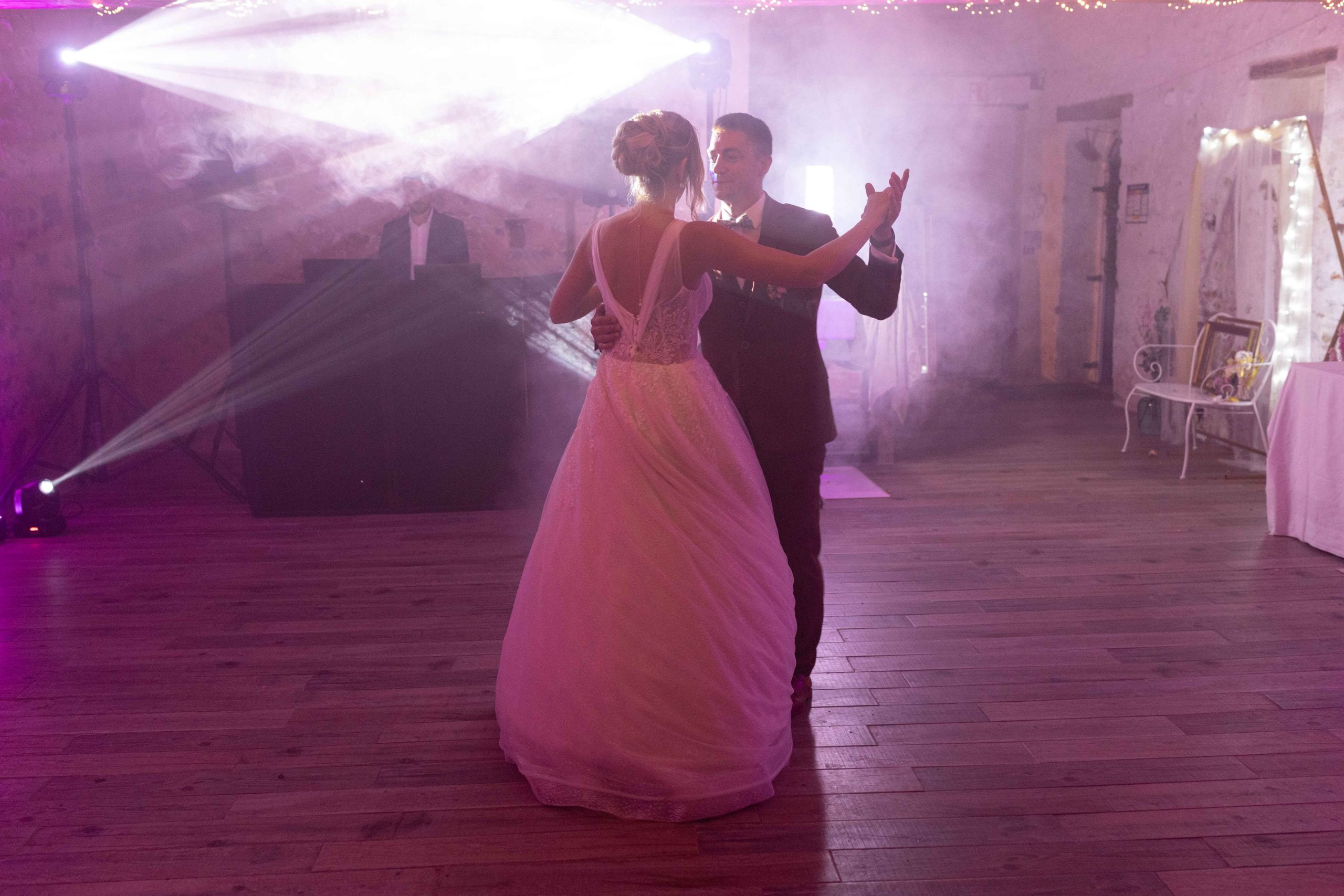 Ouverture du bal par les jeunes mariés sur une piste de danse en parquet, éclairée par des lumières violettes et une machine à fumée.