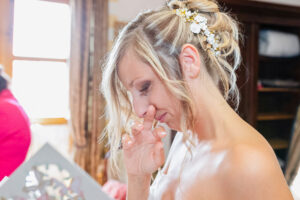 Gros plan sur le profil de la mariée essuyant délicatement une larme d'émotion, mettant en valeur son accessoire de coiffure fleuri.