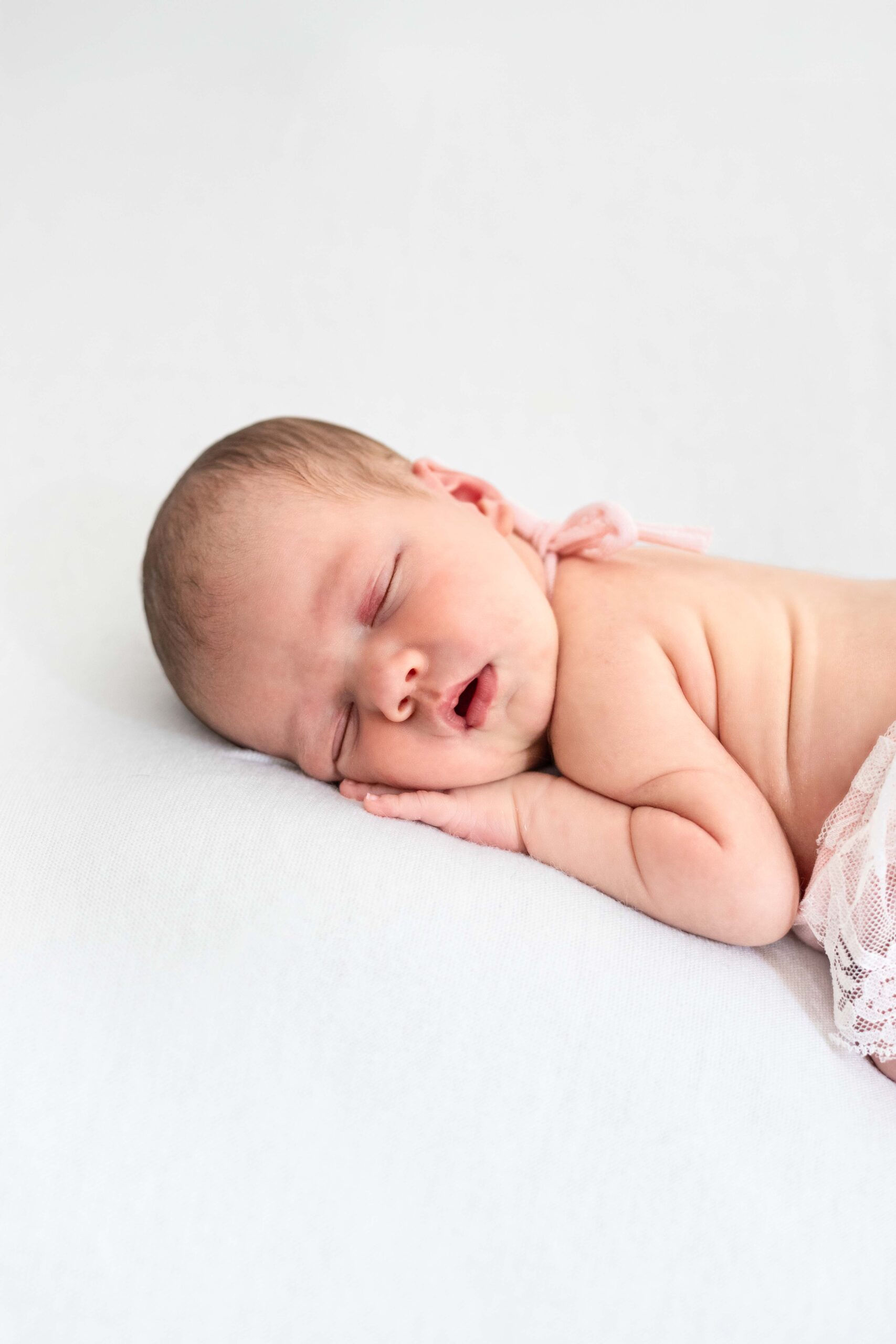 Gros plan sur le visage apaisé d'un nourrisson endormi lors de sa séance photo de naissance autour de Deauville.