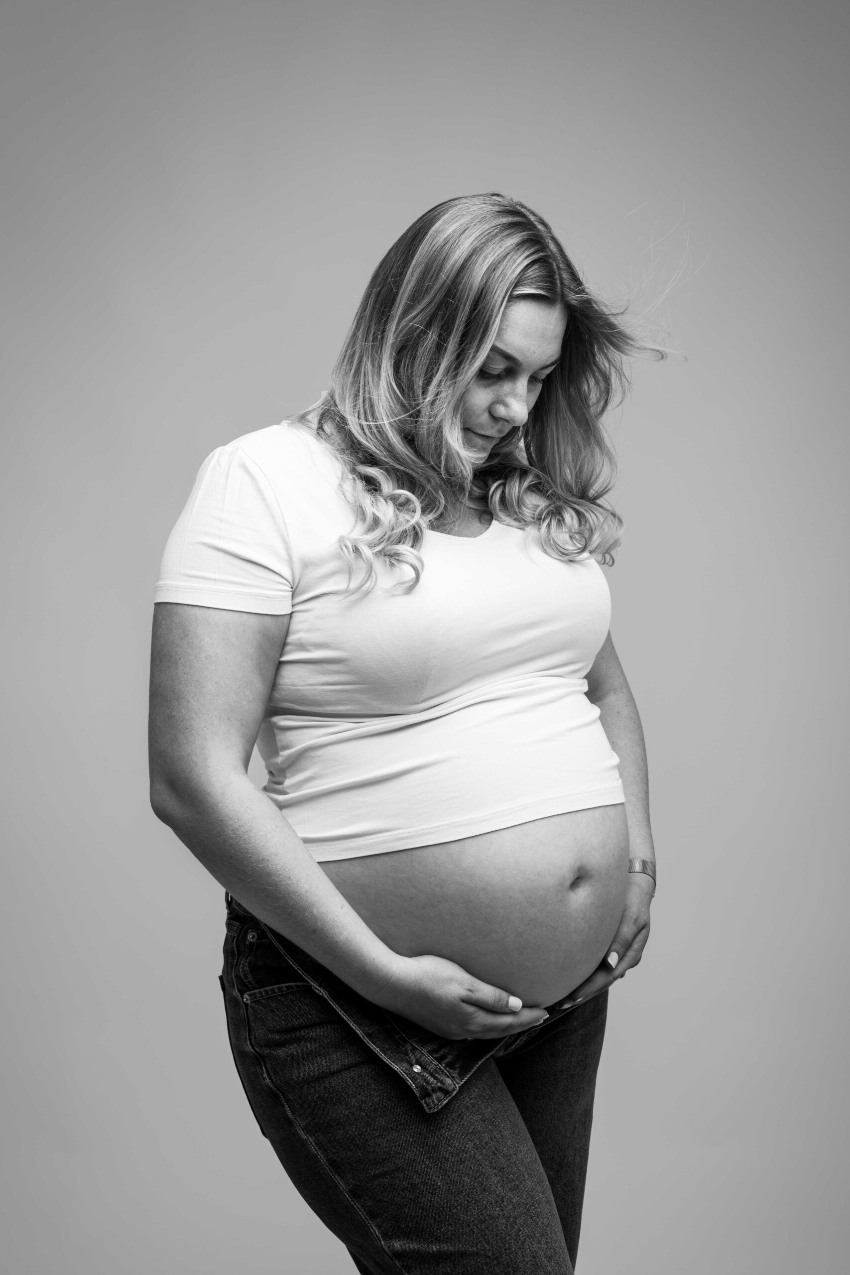 Portrait naturel en noir et blanc d'une future maman en jean et t-shirt blanc, photographe grossesse Caen.