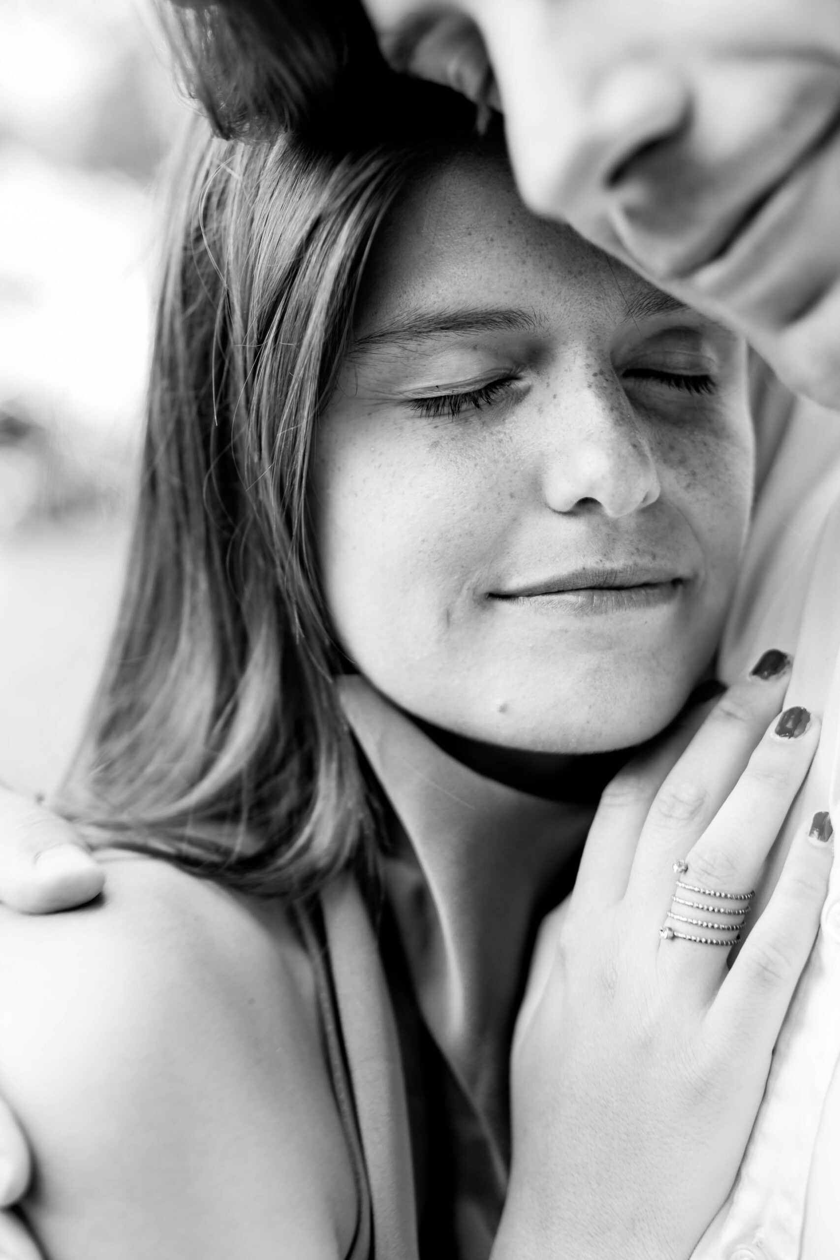 Photographie en noir et blanc pleine de tendresse d'une jeune femme enlaçant son compagnon avec émotion.